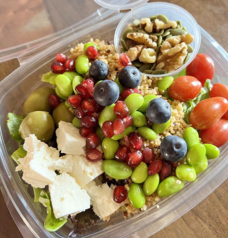 Chicken salad with boiled eggs, tuna, cucumber, cherry tomatoes, and edamame beans served with dressing